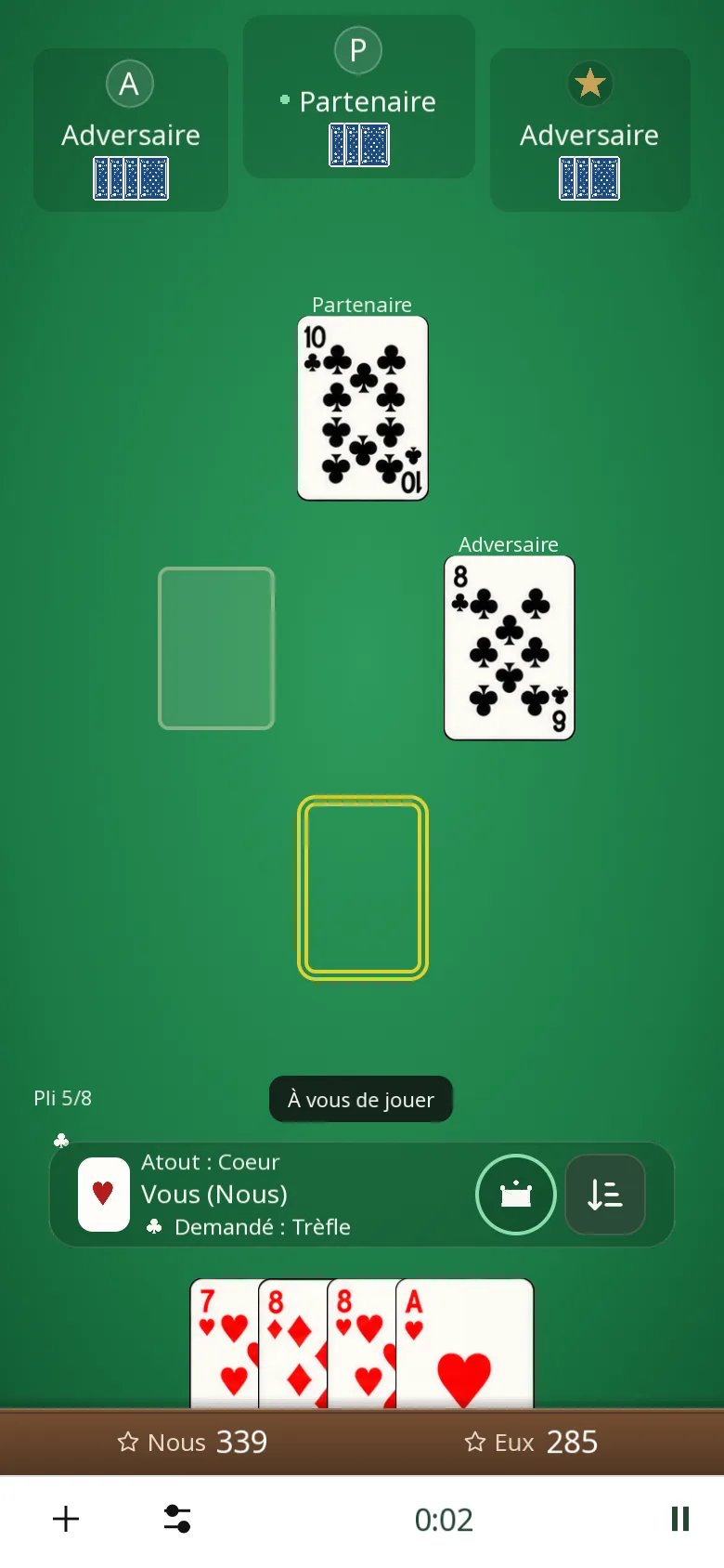 Variante Avec atout sur téléphone : atout cœur, Sud preneur, trèfle demandé ; le partenaire est maître, toutes les cartes de Sud restent jouables. Scores des deux équipes en bas de l’écran.